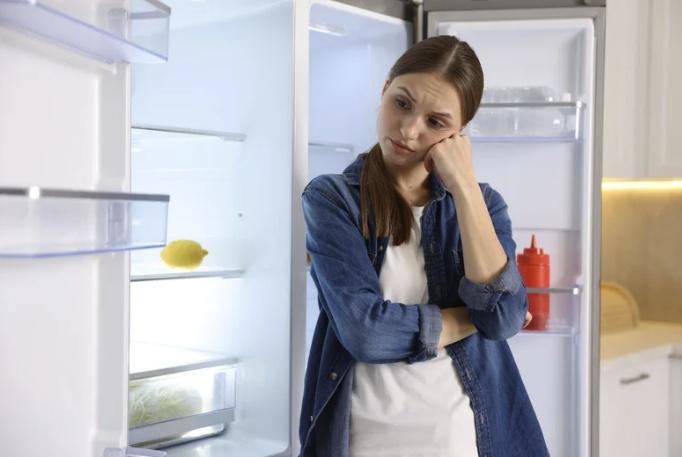 woman in deep thought with her refrigerator and freezer doors open