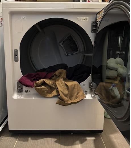 Open front-load dryer in a New Jersey home with a small load of clothes inside, showing the drum and interior moisture sensor area for a local appliance repair inspection.Select 70 more words to run Humanizer.